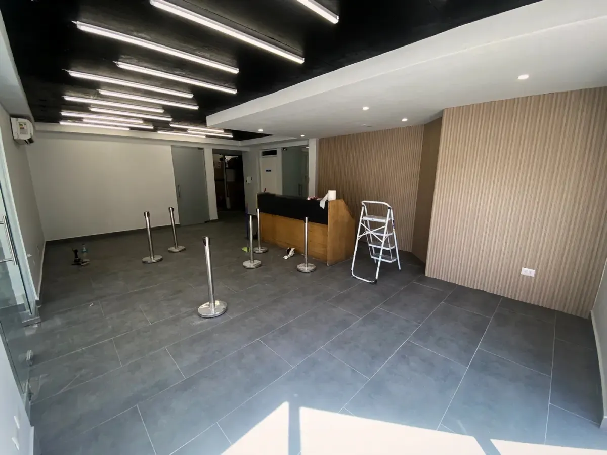 Recepción de la clínica terminada, con mesón, muro de listones y luces lineales